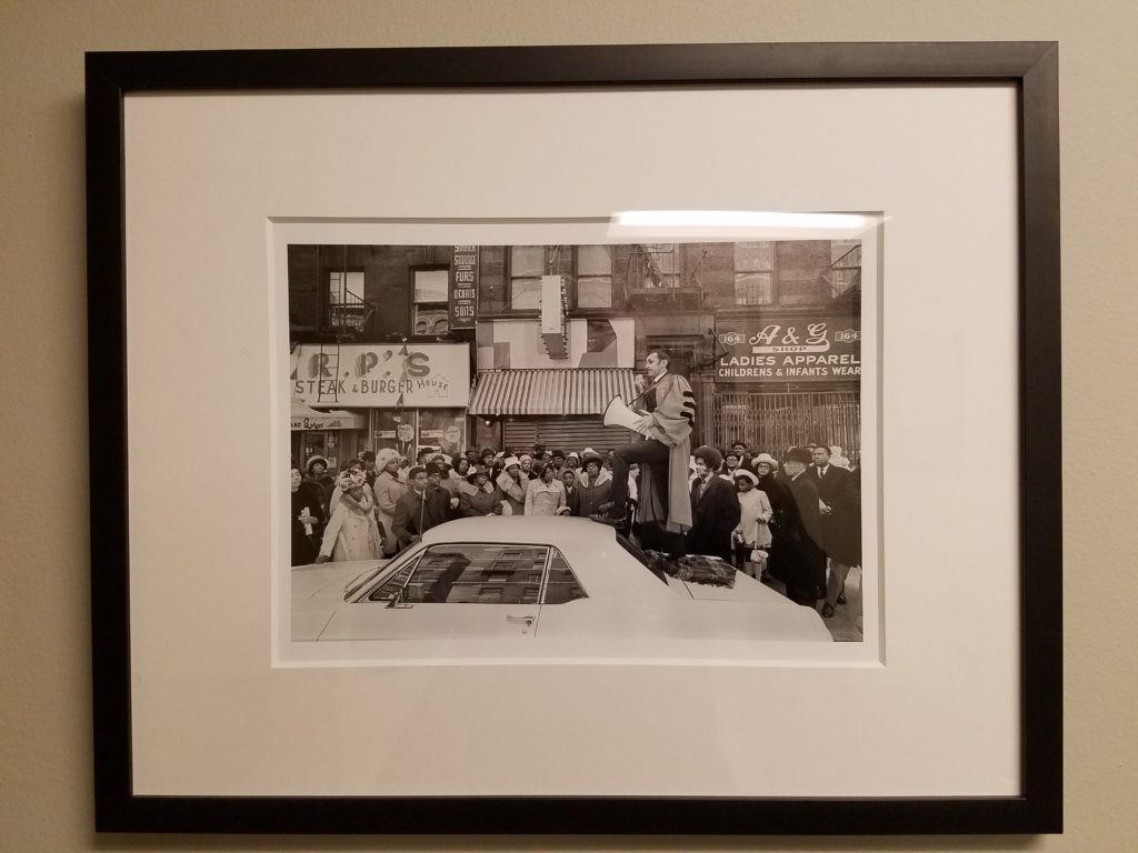 Photograph of Dr. Walker preaching through a bullhorn atop a car in Harlem, NYC.
