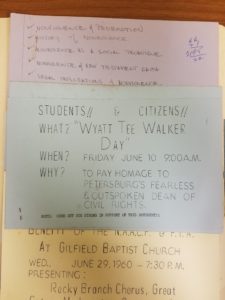 A photograph of a small, blue piece of paper. Written in all capitals the paper reads "students & citizens: Wyatt Tee Walker Day, Friday June 10 9:00AM to pay homage to Petersburg's fearless & outspoken dean of civil rights"