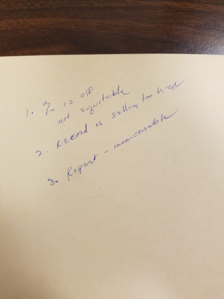 Handwritten notes in blue ink on the inside flap of a manila folder reading "% is off not equitable, record is selling too high, report - inconceivable"