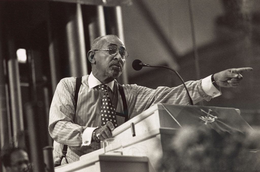 A black and white photograph of Dr. Walker leaning over a pulpit and pointing out while speaking.